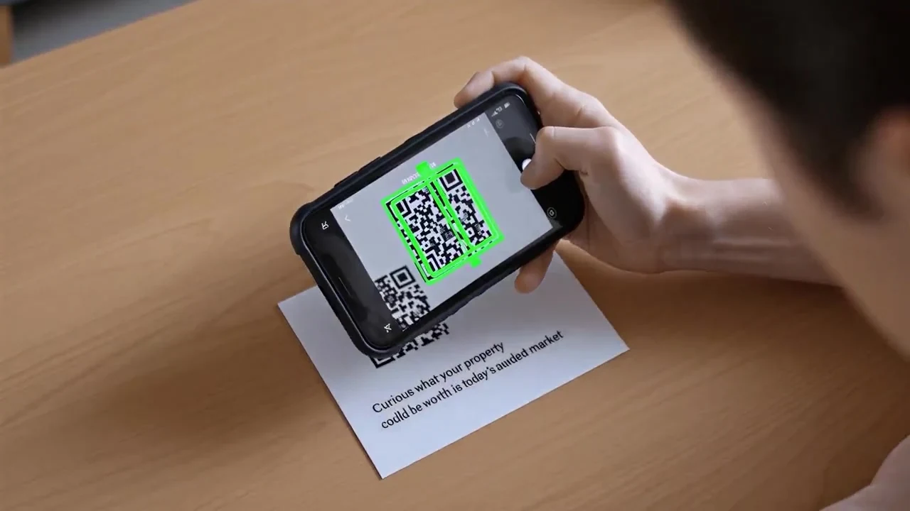 Hand scanning the QR code on a Farmrix postcard with a phone